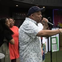John Tillery performing at an outdoor event with microphone