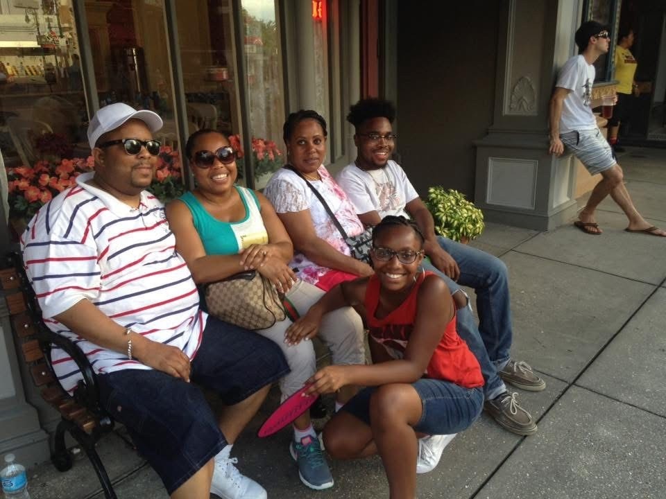 Group of five people sitting together on a city street bench