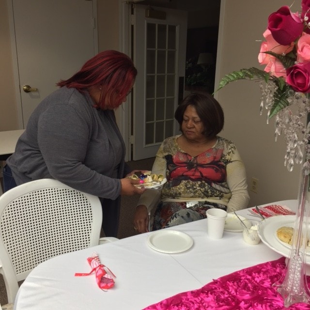 Two women at a ministry fellowship table with floral decorations