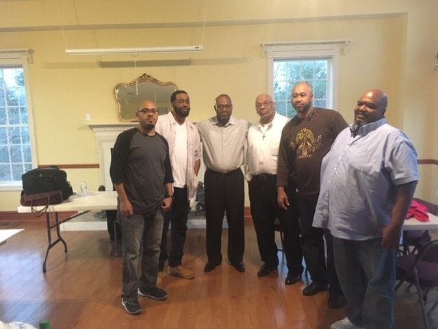 Group of six men posing together indoors at ministry gathering