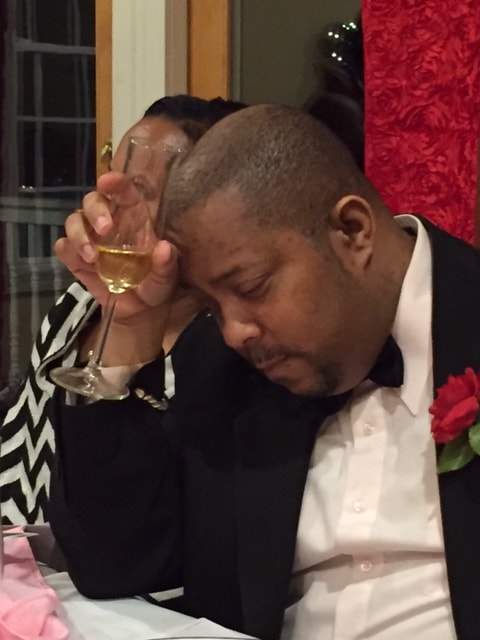 Man bowing head in prayer at formal dinner event