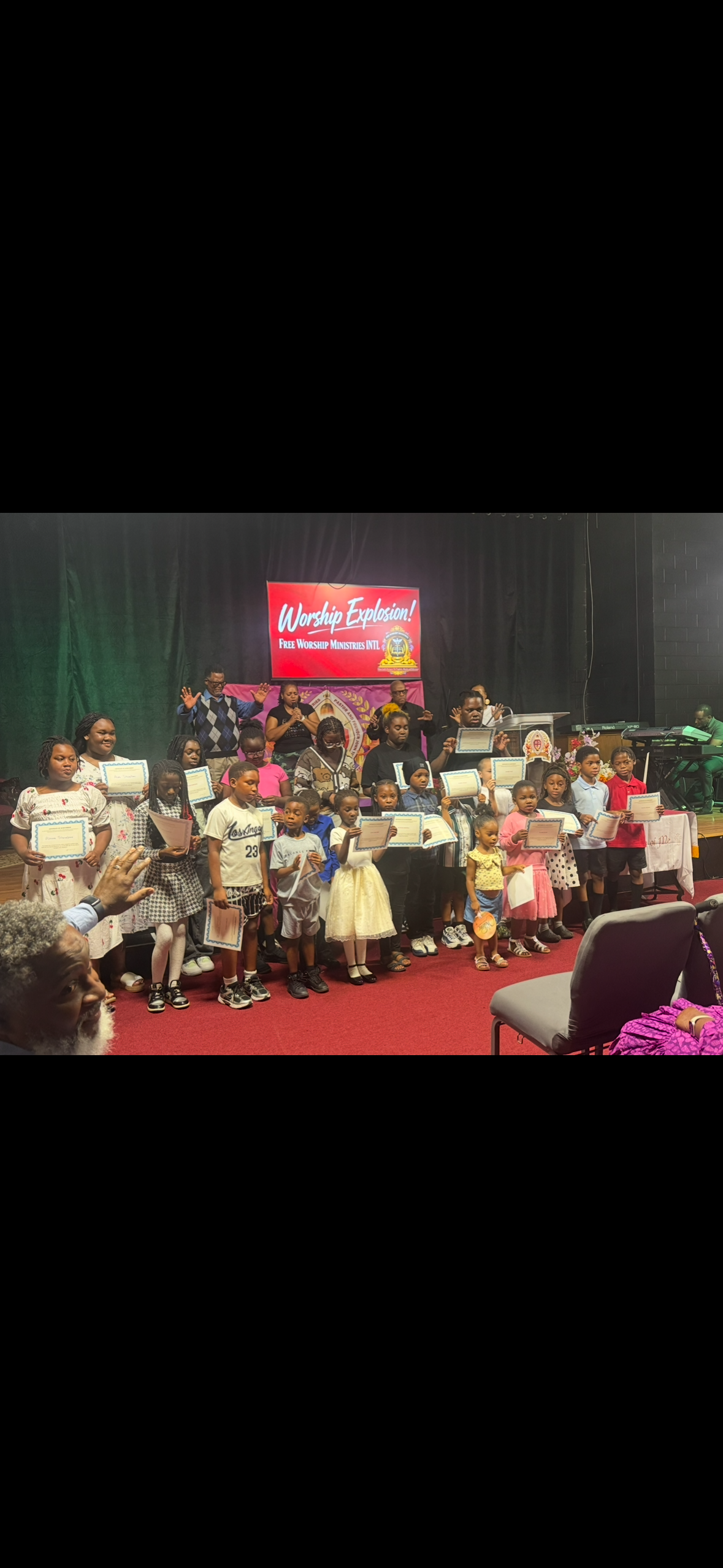 Children holding certificates on stage at Worship Explosion — Free Worship Ministries INTL