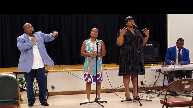 John Tillery and choir performing on stage with Roland keyboard
