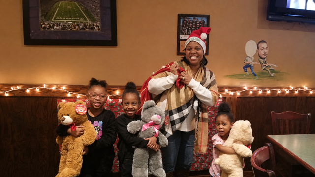 Woman and three children with stuffed animals at Christmas gathering